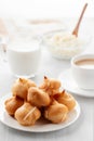 Morning coffee with cakes. Profiteroles, coffee, cream, cottage cheese on a white wooden table. Vertical image