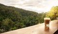 Morning coffee concept. hot coffee cup on wooden with lush green jungle background, sunrise through the forest, copy-space Royalty Free Stock Photo