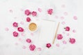 Morning coffee cup for breakfast, empty notebook, pencil and pink rose flowers on white stone table top view in flat lay style.