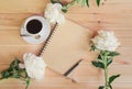 Morning coffee cup for breakfast, empty notebook and white peony flowers on wooden table