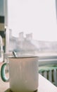 Morning coffee cup with a teaspoon in a kitchen with sunrise and cityscape