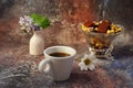 Morning coffee in a hurry: a cup of coffee, flowers in a vase, dried fruits and sweets in a vase, a burning candle Royalty Free Stock Photo