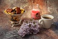 Morning coffee in a hurry: a cup of coffee, flowers in a vase, dried fruits and sweets in a vase, a burning candle Royalty Free Stock Photo