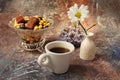 Morning coffee in a hurry: a cup of coffee, flowers in a vase, dried fruits and sweets in a vase, a burning candle Royalty Free Stock Photo