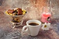 Morning coffee in a hurry: a cup of coffee, flowers in a vase, dried fruits and sweets in a vase, a burning candle Royalty Free Stock Photo