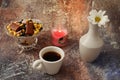 Morning coffee in a hurry: a cup of coffee, flowers in a vase, dried fruits and sweets in a vase, a burning candle Royalty Free Stock Photo