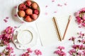 Morning coffee mug for breakfast, fresh lichee fruit, empty notebook, pen and pink flowers on white wooden table, top view, flat