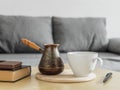 Morning coffee still life in the interior. Coffee cup, cezve and books on table, gray sofa background. Stay home concept Royalty Free Stock Photo