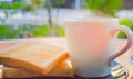 Morning coffee and toasted whole wheat bread on black plate on the red table with smoke over the cup of coffee in the sunshine.