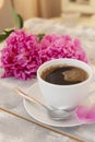 Morning coffee in a white cup and beautiful pink peony flowers on a whitewashed light table. Cozy romantic coffee break Royalty Free Stock Photo