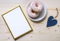 Morning composition with donuts on a wooden table. Gold frame for the presentation of works or text.