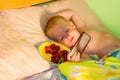 Morning at the cottage - a little boy with blond hair and blue eyes lies on the bed, happily squinting at the sunlight and Royalty Free Stock Photo