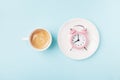 Morning cup of coffee and alarm clock on blue working desk top view. Breakfast time concept. Flat lay style. Royalty Free Stock Photo