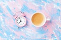 Morning cup of coffee and alarm clock on colorful working desk top view in flat lay style. Punchy pastel background. Royalty Free Stock Photo