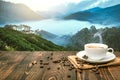 Morning cup of coffee and coffee beans with mountain background at sunrise. Beauty mountain landscapes