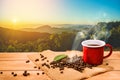 Morning cup of coffee and coffee beans with mountain background at sunrise. Beauty mountain landscapes