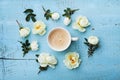 Morning cup of coffee and beautiful roses flowers on blue vintage background top view. Cozy Breakfast. Flat lay style. Royalty Free Stock Photo