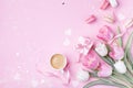 Morning cup of coffee, cake macaron, gift box and spring tulip flowers on pink background. Beautiful breakfast for Women day