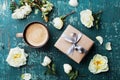 Morning cup of coffee, gift box and beautiful roses flowers on teal vintage table top view. Cozy Breakfast. Flat lay style.