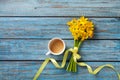 Morning cup of coffee and spring daffodil flowers on blue rustic background. Beautiful breakfast for Women day, Mother day. Royalty Free Stock Photo
