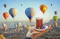 Morning cup of tea with view of colorful hot air balloons