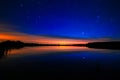 Morning dawn on starry background sky reflected in the water o Royalty Free Stock Photo