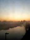 Morning dawns misty with cloudless sky above North London canal and moored boats