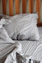 Morning empty messy bed gray bed linen, bedclothes. Sheet, blanket, pillows and wooden headboard