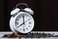 Retro alarm clock, coffee beans and cinnamon on a wooden table . Black background . Morning. Espresso . Wake up.
