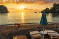 morning or evening landscape with nice beach with deck chairs and umbrellas during sunrise or sunset with amazing sea with rocks