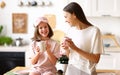 Morning with family. Happy cute little girl with young lovely mom drinking tea in the modern kitchen at home Royalty Free Stock Photo