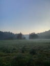 Morning fog on meadow with trees and hills with forest silhouettes Royalty Free Stock Photo