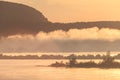 Morning fog rises over the river in the light of the rising sun against the silhouettes of mountains and Islands Royalty Free Stock Photo