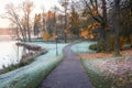 Morning foggy autumn landscape with red trees by the lake. A winding path covered with frost Royalty Free Stock Photo