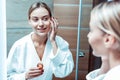 Beaming young woman staying in stylish bathroom and carrying glass container