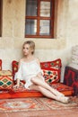 Morning girl resting sitting on a Turkish sofa. A woman in light clothes is preparing for the arrival of her beloved man Royalty Free Stock Photo