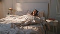 Morning girl stretching bed in sunlight. Peaceful positive model waking up early Royalty Free Stock Photo