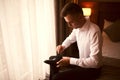 Morning of the groom before the wedding. Groom morning preparation. Young and handsome groom getting dressed in a wedding shoes