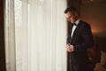 Morning of the groom before the wedding. Groom morning preparation. Young and handsome groom getting dressed in a wedding suit