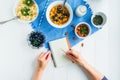 Morning habits of successful people. Day planning and healthy meal. Woman writing in notebook on the served for healthy Royalty Free Stock Photo