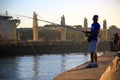 Morning in Havana. A fisherman on the embankment against the background of a passing cargo ship