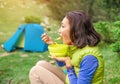 Hot breakfast in the woods - Woman hiker eating hot meal near the tent while camping in mountains