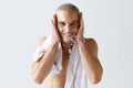 Morning hygiene. Handsome, smiling, young man washing his face, taking care after skin against white studio background Royalty Free Stock Photo