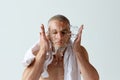 Morning hygiene. Handsome young man washing his face, taking care after skin against white studio background Royalty Free Stock Photo