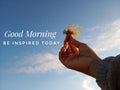 Morning inspirational quote- Good morning. Be inspired today. With blurry image of young woman hands holding sea weed against the