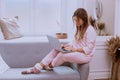 In the morning a lady in pink pajamas working in living room on the notebook, modern design Royalty Free Stock Photo