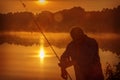 Morning on the lake dawn. A fisherman is standing on the shore next to fishing rods