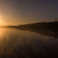 Morning on the lake in the forest with fog or steam on the background of the sun Royalty Free Stock Photo