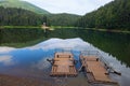 Morning landscape of mountain Synevyr Lake with two wooden floats at the shore. Old high trees near the lake. Royalty Free Stock Photo