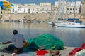 Morning landscape photo made in Gallipoli pier, fishermen reparing his fishermen net after fishing, Apulia, Italy